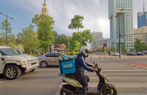 Wolt food delivery courier navigating city traffic on a scooter